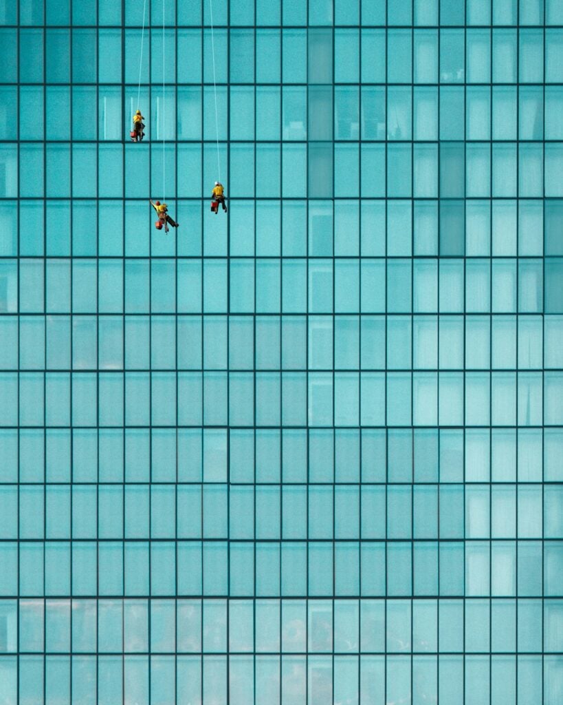 Three window cleaning professionals working together on a building exterior